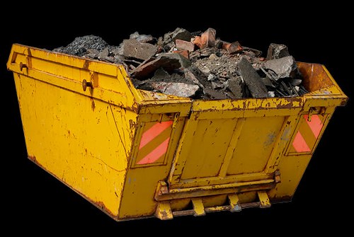 A large yellow skip filled with broken concrete, bricks, and rubble sits on a paved surface, likely part of a building or yard clearance associated with waste removal services in Finchley. The skip's sides are made of metal with a ribbed texture and show signs of use, including dirt and minor rust spots. The rubble includes dark gray concrete chunks, reddish-brown bricks, and smaller fragments scattered throughout, with some pieces leaning against the sides of the skip. The background is plain black, highlighting the skip and its contents, which appear to be freshly collected debris awaiting removal. This scene reflects the type of waste typically handled by commercial waste services in the Finchley area, emphasizing the company's capacity to manage construction or renovation debris efficiently. The positioning suggests the skip is ready for transportation or ongoing loading, fitting within the context of professional rubbish removal work in north London.